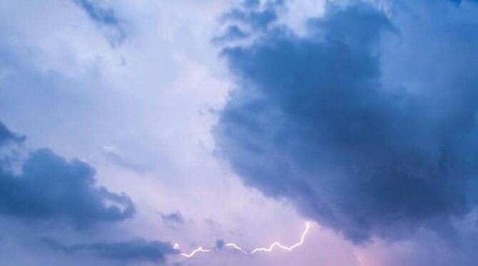 Blitz leuchtet zwischen den Wolken am Himmel
