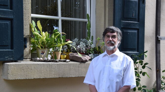 Pfarrer Thomas Kurz unter dem Fenster seines Arbeitszimmers, mit Pflanzen und Schneckenhäusern auf dem Sims. FOTO: GEIGER