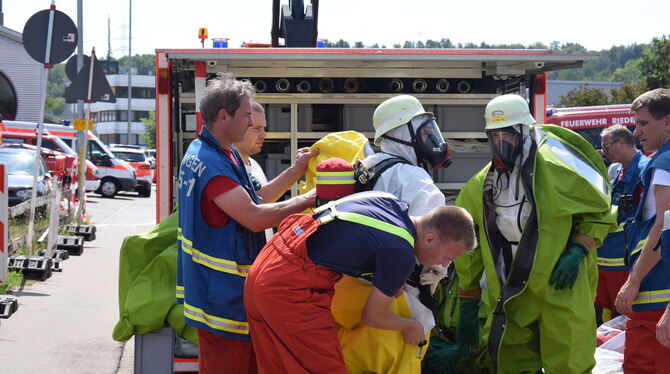 Fertig machen für den Ernstfall: Feuerwehrleute mit Schutzanzügen und Atemmasken untersuchten die schadhaften Gasflaschen vor de