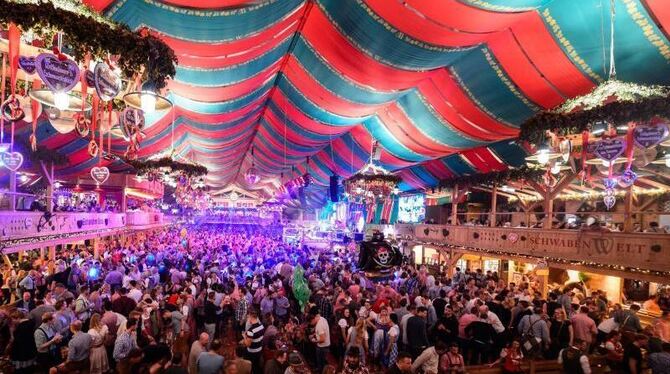 Besucher feiern in einem Zelt beim Cannstatter Volksfest
