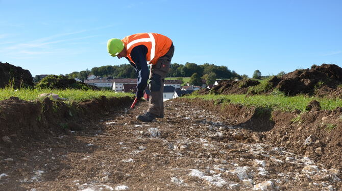 Grabungstechniker Jean Gundermann sucht nach Auffälligkeiten in den gezogenen Gräben in Holzelfingen.  FOTO: SAUTTER