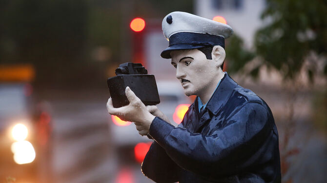 Eine lebensgroßes Puppe, die als Polizist lackiert ist, steht in der Ortsdurchfahrt von Musbach und hält eine Kamera in der Hand