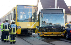 Eine Stadtbahn und ein Linienbus stehen nach einem Zusammenstoß im morgendlichen Berufsverkehr auf einer Straße. Mehrere Mensche