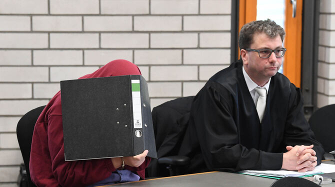 Der 34 Jahre alte Schwimmlehrer im Landgericht Baden-Baden mit einem Aktenordner vor dem Gesicht.