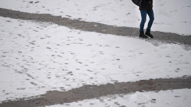 Frau geht einen vom Schnee geräumten Weg entlang
