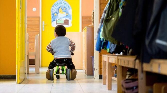 Ein Junge fährt in einer Kindertagesstätte mit einem Bobbycar
