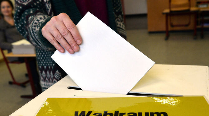 Eine Frau steckt in einem Wahllokal ihren Stimmzettel in eine Wahlurne. FOTO: DPA
