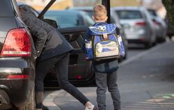 Ein Grundschüler steht neben einem Auto