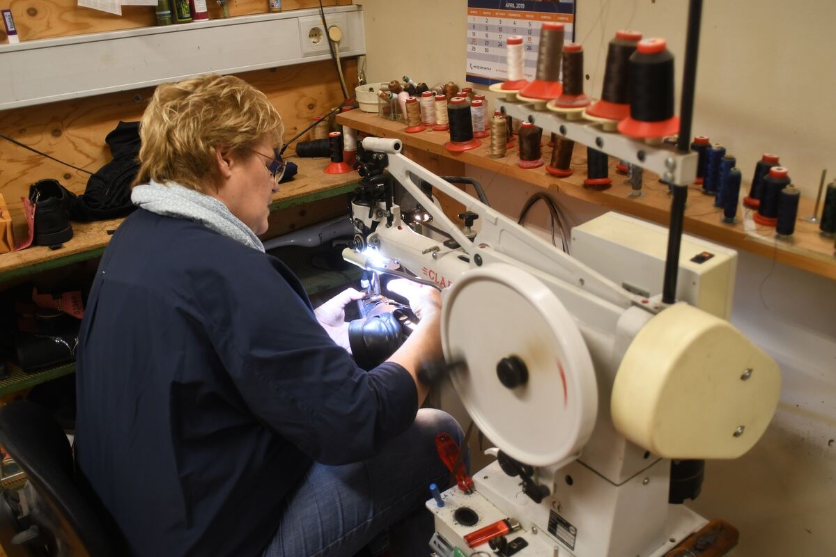 Frau Staneker näht spezielle Gummizüge in Sandalen.