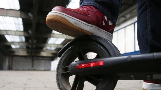 Mann tritt auf Bremse eines Elektro-Tretrollers