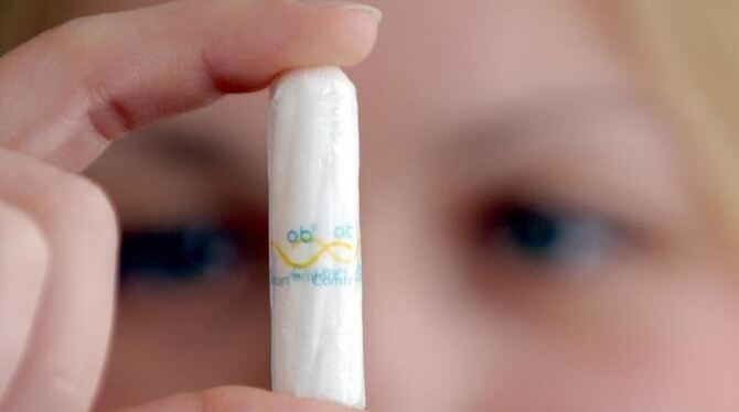 Eine Frau hält einen Tampon in die Kamera.