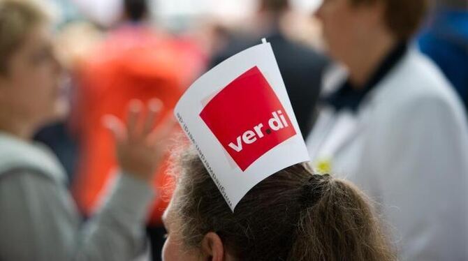 Eine Frau hat eine Verdi-Fahne in den Haaren stecken