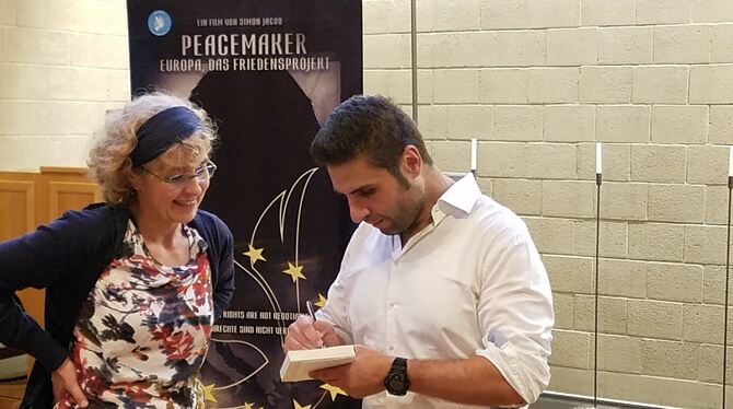 Simon Jacob signiert in Reutlingen für eine Besucherin seines Vortrages eines seiner »Peacemaker«-Bücher. FOTO: RAHMIG