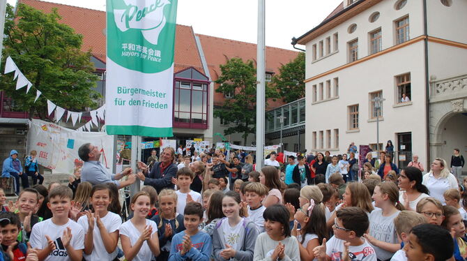Gesäumt von unzähligen Schülern hissen OB Ulrich Fiedler und Werner Schulz vom AK Frieden die »Mayors for Peace«-Flagge.
