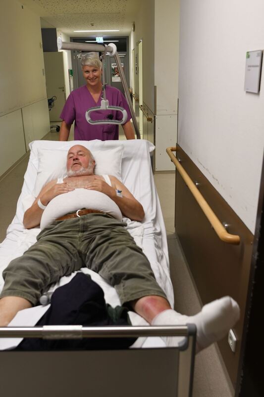 Der ältere Herr mit dem entzündeten Fuß wird von Pflegerin Nadine Zirlewagen charmant durch den Gang geschoben.