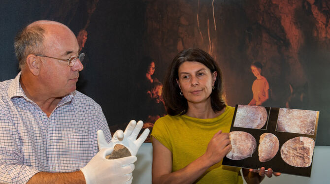Nicholas Conard mit dem Originalstein und Grabungsleiterin Maria Malina mit vergrößerten Aufnahmen des gefundenen Objekts. Foto: