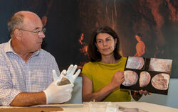 Nicholas Conard mit dem Originalstein und Grabungsleiterin Maria Malina mit vergrößerten Aufnahmen des gefundenen Objekts. Foto: