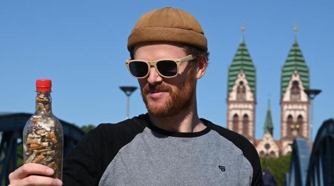 Till Neumann hält eine Plastikflasche mit Zigarettenstummeln