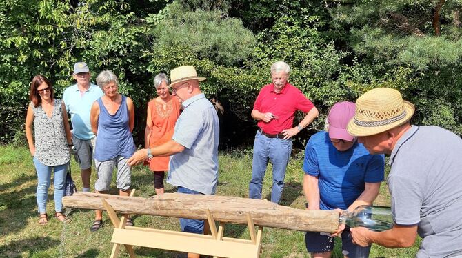 Günter Eissler zeigt, dass das alte Holzrohr, eine Teuchel, noch gut funktioniert: Hinten wird Wasser hineingeschüttet, vorne lä