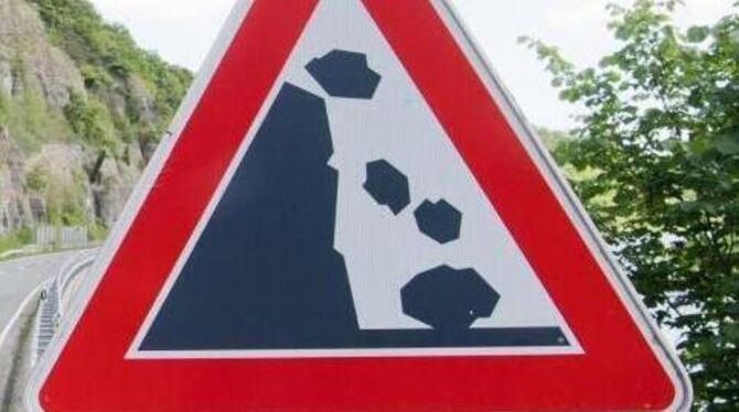 Ein Schild warnt an einer Straße vor Steinschlag