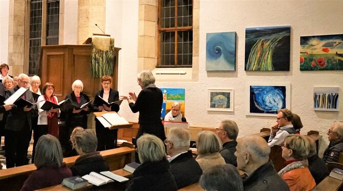 Der Evangelische Kirchenchor unter Leitung von Anja Schmid singt, rechts an der Wand sind Bilder der Malgruppe. Foto: Straub