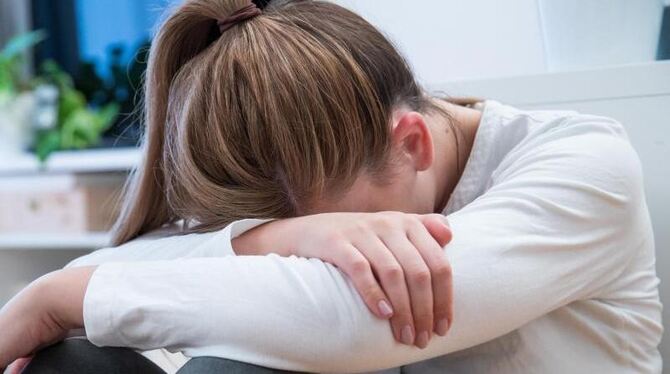 Depression, Angststörung Eine Frau sitzt verzweifelt auf dem Boden.