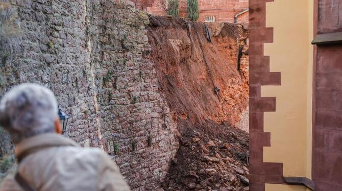 Eine Frau betrachtet eine eingestürzte historische Mauer