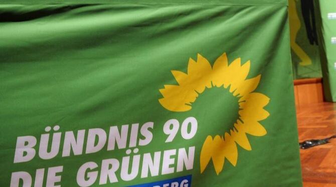 Ein Logo der Partei die Grünen hängt über einem Tisch