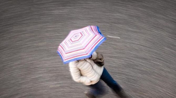 Eine Frau geht bei Regen über eine Straße
