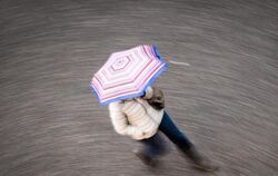 Eine Frau geht bei regnerischem Wetter durch die Innenstadt