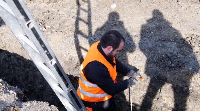 Mitarbeiter im Umbettungsdienst untersucht Baugrube