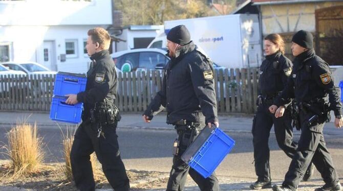 Polizisten überqueren mit blauen Kisten in den Händen eine Straße