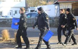 Polizisten überqueren mit blauen Kisten in den Händen eine Straße