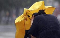 Eine Frau kämpft mir einem Regenschirm gegen Windböen