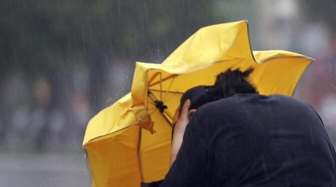 Eine Frau kämpft mir einem Regenschirm gegen Windböen