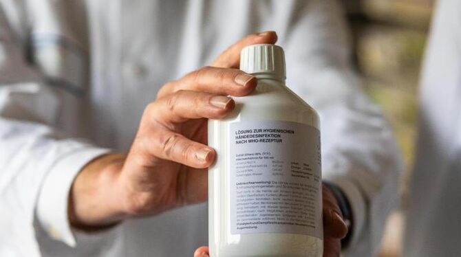 Ein Apotheker hält eine Flasche Desinfektionsmittel