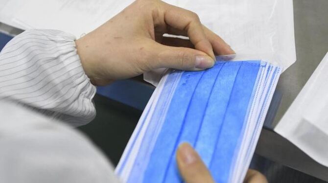 Ein Mitarbeiter verpackt Schutzmasken. Symbolbild