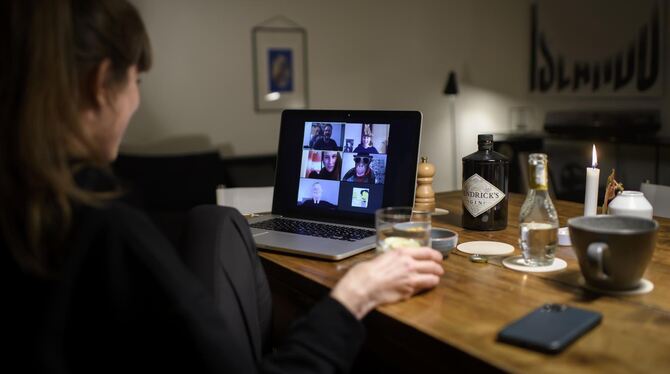 Eine Frau sitzt während der Corona-Pandemie an einem Tisch in ihrer Wohnung vor einem Laptop, während sie mit weiteren fünf Pers