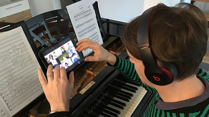Chorleiter Christian Bonath gibt bei einer digitalen Chorprobe vom Flügel aus Anweisungen an die jugendlichen Sänger, die per Vi