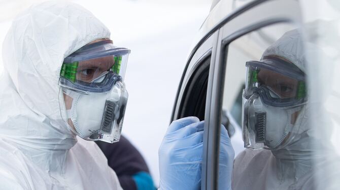 Im Drive-in wird mit einem Stäbchen ein Abstrich bei einem Autofahrer gemacht. FOTO: DPA Im Drive-in wird mit einem Stäbchen ein Abstrich bei einem Autofahrer gemacht. FOTO: DPA