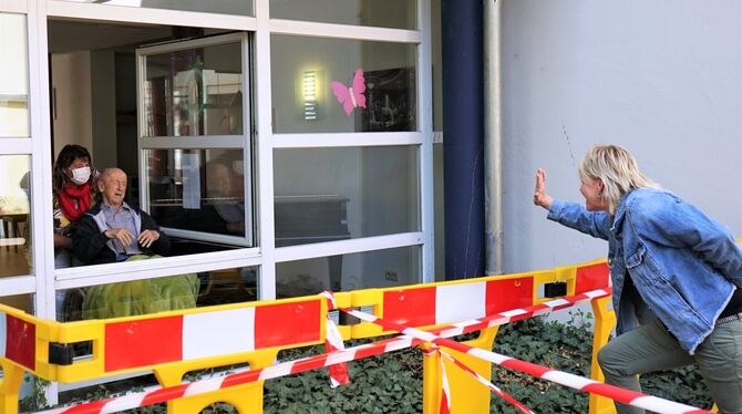 Pflegedienstleiterin Sabine Janecek bringt Ernst Holaschke (89) ans Fenster, seine Tochter Sabine Broghammer grüßt hinter dem Ba