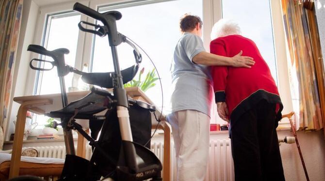 Eine Pflegerin blickt mit einer Heimbewohnerin aus dem Fenster