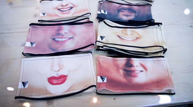 Fotomasken als Mund-Nasen-Schutz liegen in einer kleinen Textildruckerei in Hamburg-Winterhude auf einem Tisch.