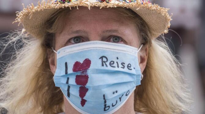»Ich liebe Reisebüros« steht auf dem Mundschutz der Demonstrantin