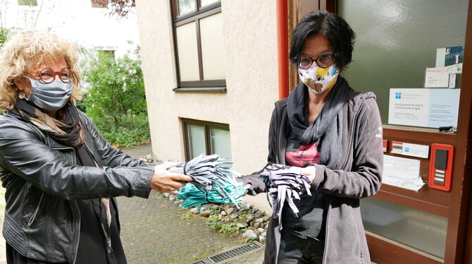 Beate Müller-Gemmeke (links) übergibt Asylpfarrerin Ines Fischer genähte Behelfsmasken, die bei hohen Temperaturen gewaschen wer