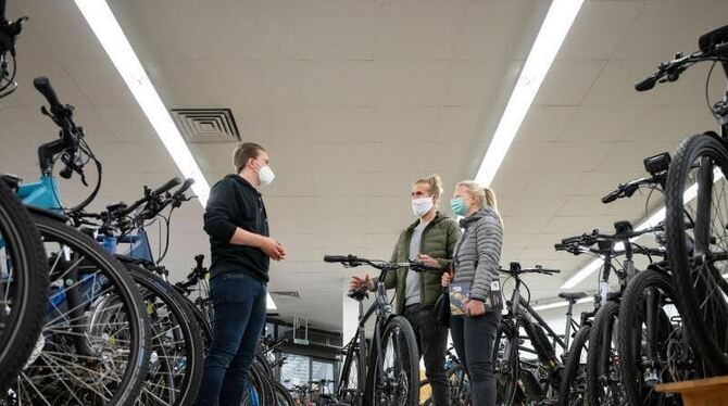 Ein Angestellter eines Fahrradlades berät Kunden Ein Angestellter eines Fahrradlades berät Kunden