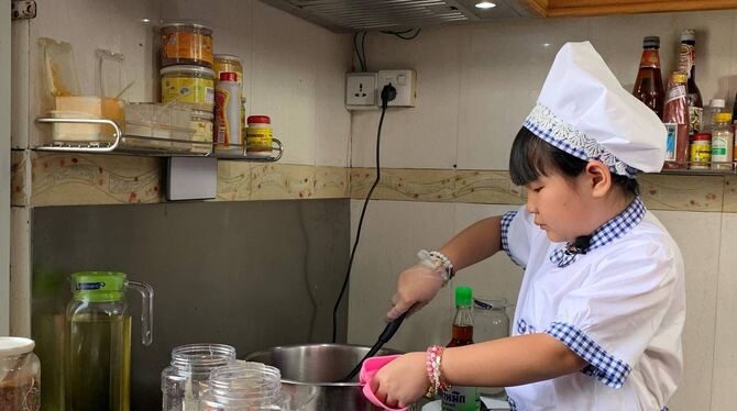 Die achtjährige Moe Myint May Thu beim Kochen in ihrer Küche. Sie ist während des Lockdowns in Myanmar zu einer kleinen Starköch