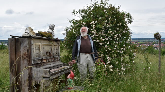 Hartmut Gaebele zwischen Rosenbusch und arrangiertem Klavier-Stillleben im jetzt wieder zugänglichen Rosenpark auf der ehemalige