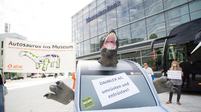 Ein Demonstrant in einem SUV-Kostüm mit einem Dinosaurierkopf steht anlässlich der Daimler-Online-Hauptversammlung des Konzerns