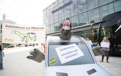  Ein Demonstrant in einem SUV-Kostüm mit einem Dinosaurierkopf steht anlässlich der Daimler-Online-Hauptversammlung des Konzerns
